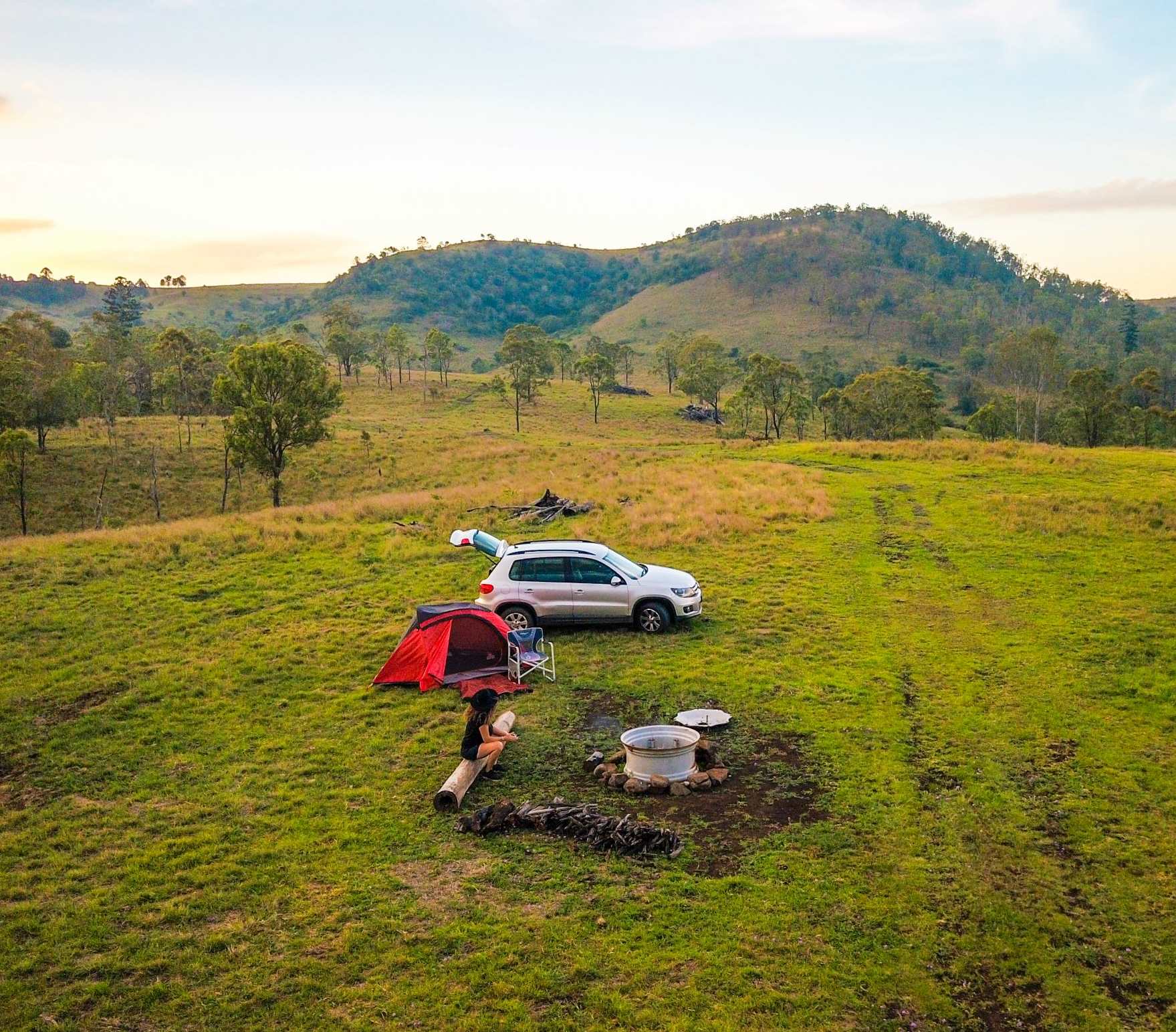 Car and tent set up on a grassy hilltop