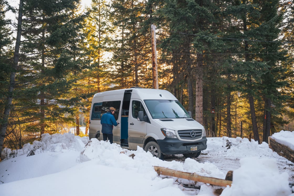 A man opens the sliding door of his camper van in the snow