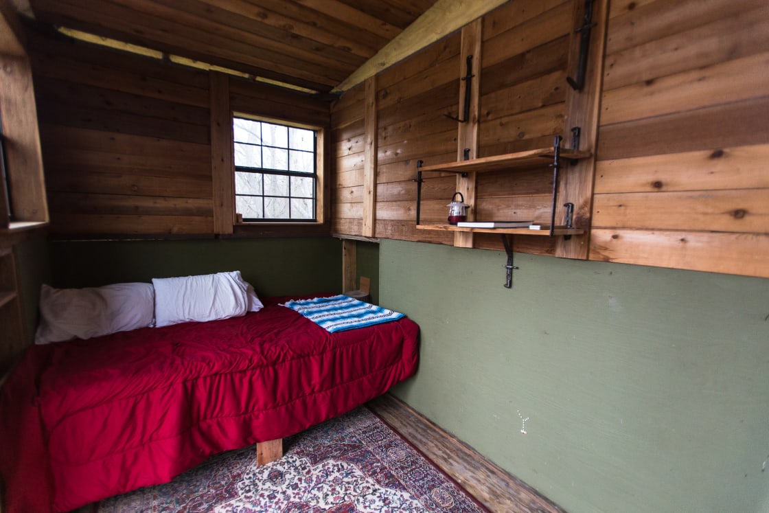 The treehouse bed snuggly fits two people. BYOSB (bring your own sleeping bag!).
