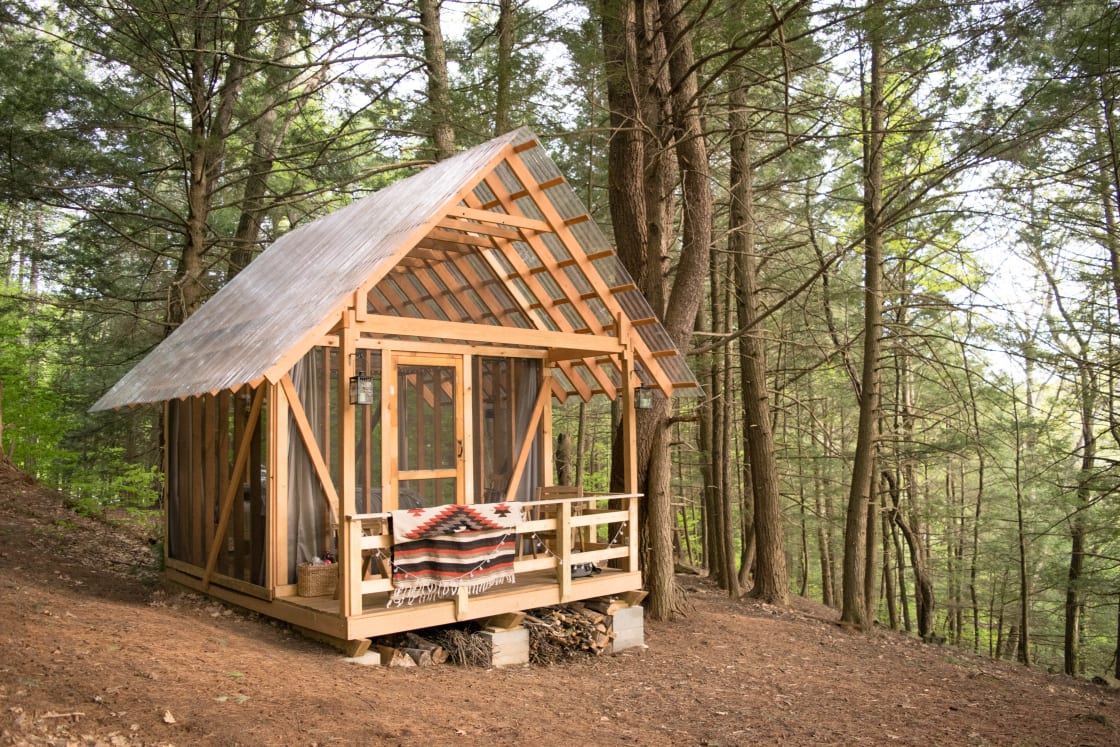 An open-air tiny cabin in the Vermont forest. Screened "walls" let in the summer breeze - and keep out the bugs.