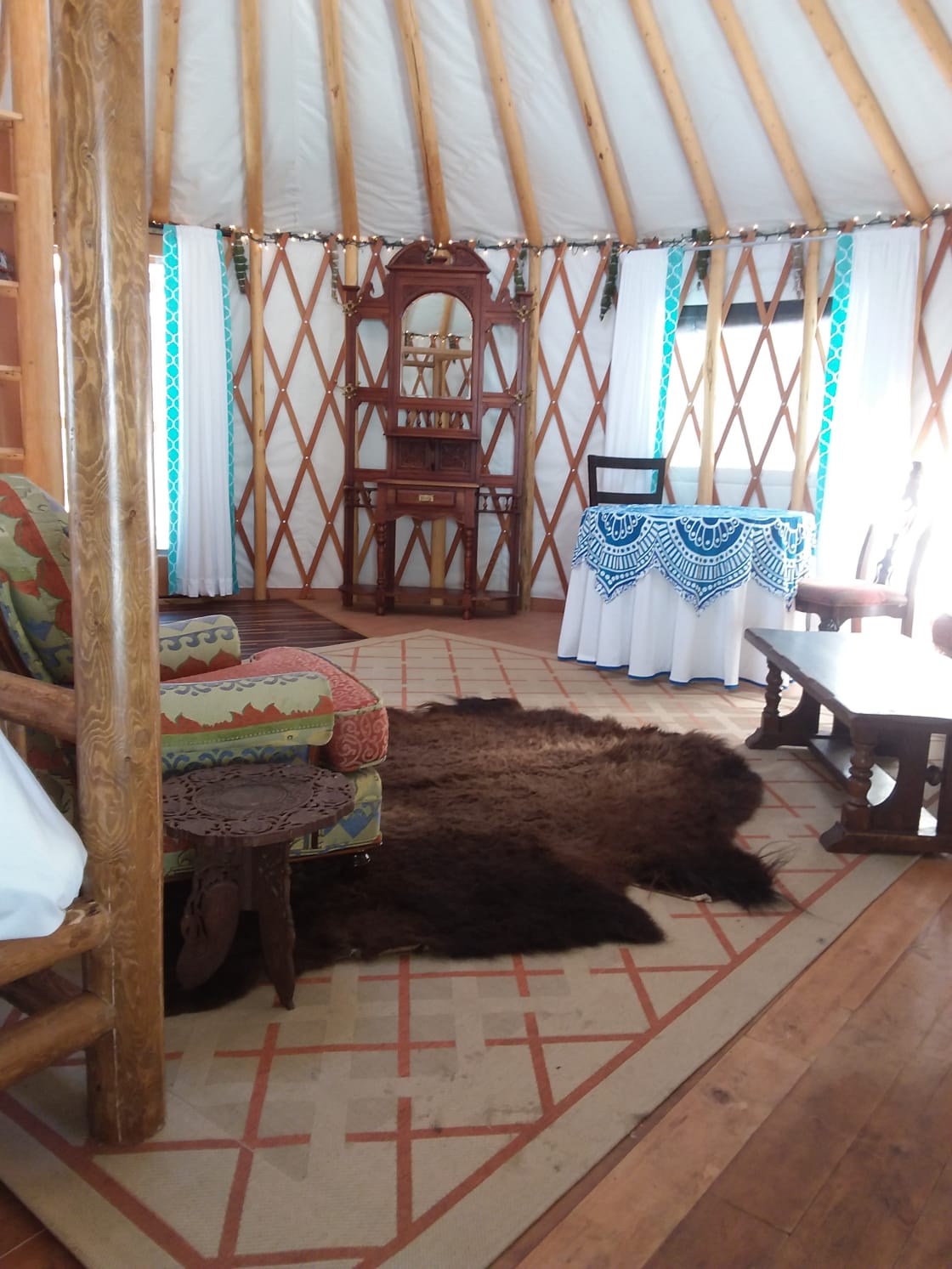 Interior Yurt, complete with comfy king size bed (and bedding), couch, table and chairs, bookcase and wood stove, 
