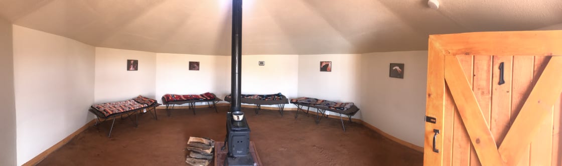 The inside of the Navajo Hogan with cots, firewood and fire stove.
