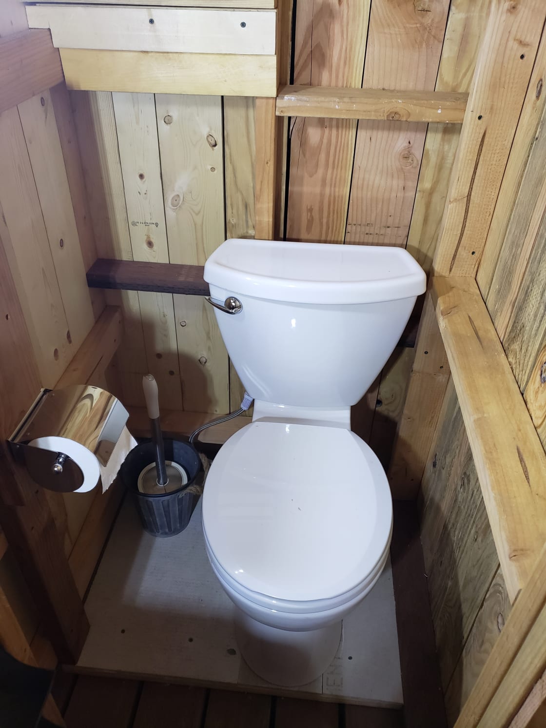 Our proper flushing porcelain toilet has a slow filling, gravity-fed water tank in the private all gender bathroom shared by both camps.  This picture was taken at night without a flash, showing the ample available light with both LED light switches turned on.