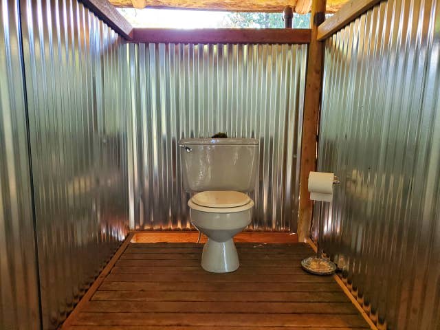 Outdoor campground-style covered restroom & shower in cedar forest adjacent to the cabin.
