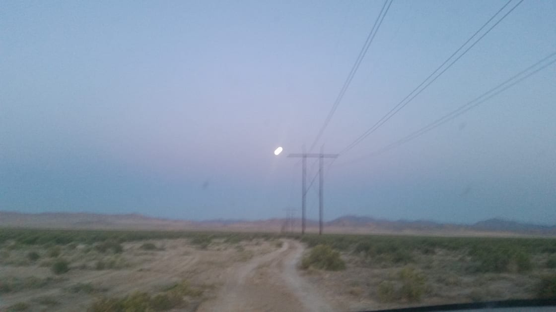Giant full moon coming up over the power poles on the road in...