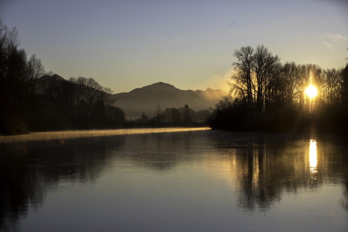 The sun rises over the Skagit River and the camping spot on the right.
