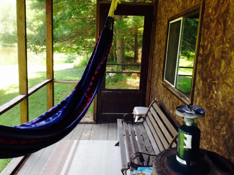 The cabin's screened-in front porch faces the pond and you may hang one hammock there. 
