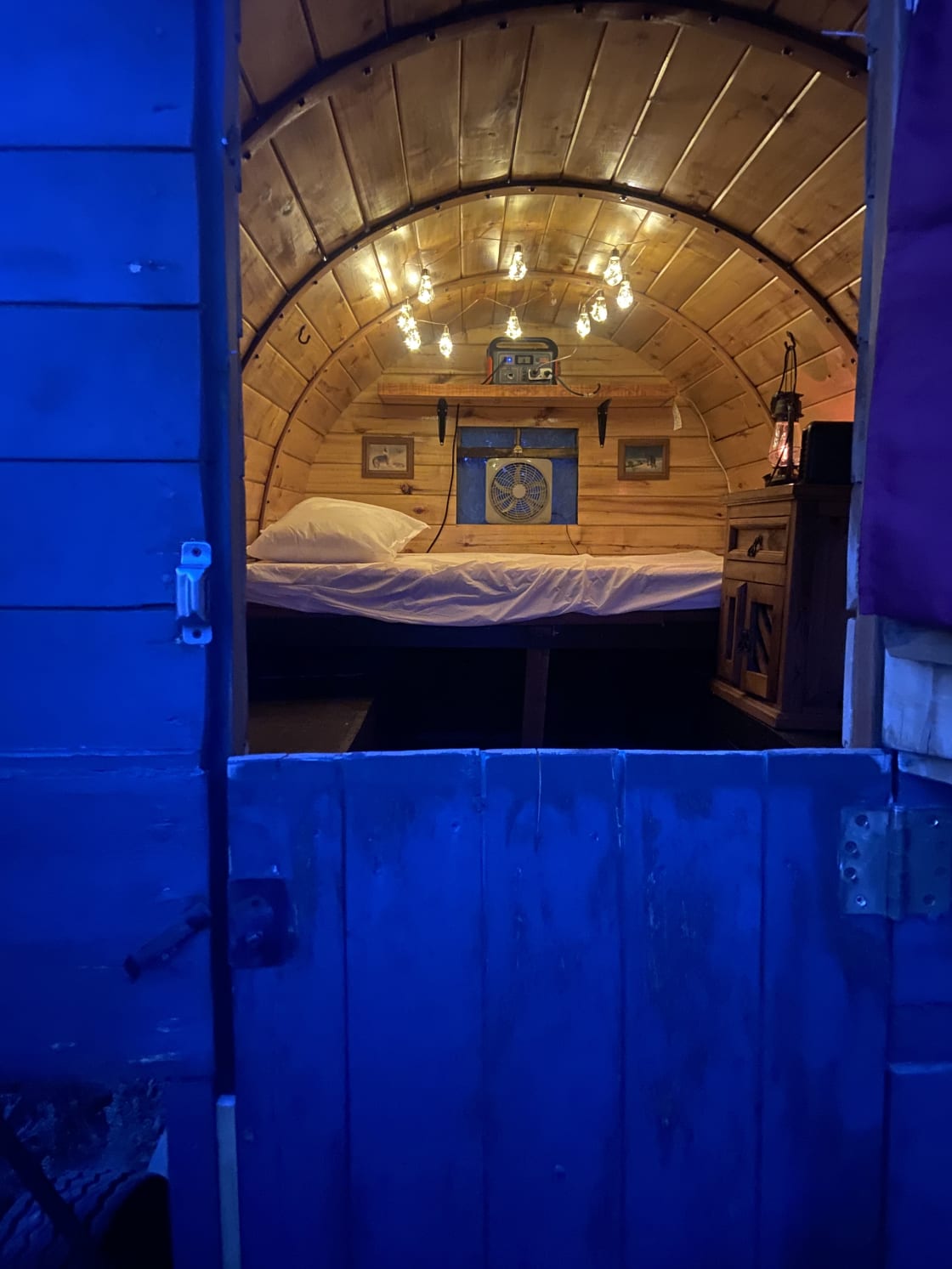 Inside of sheep herder cabin with mattress folded out and table pulls out underneath