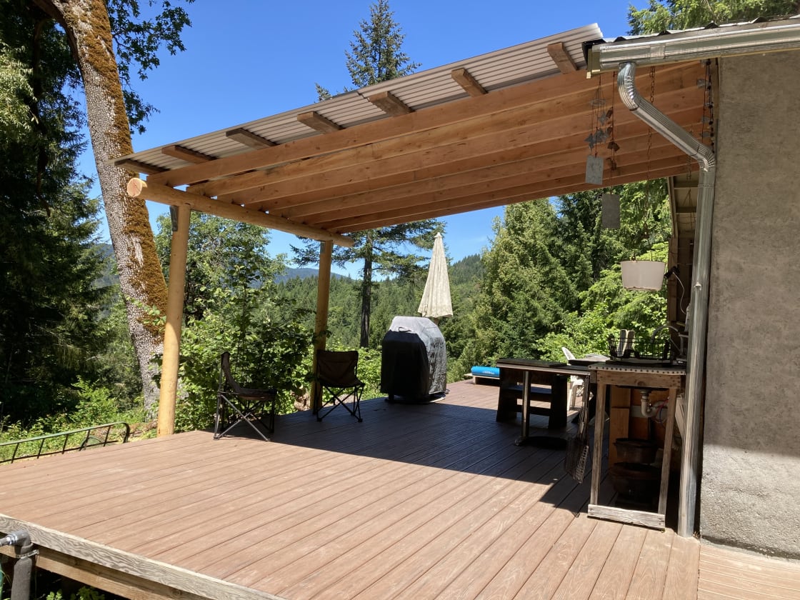 Outdoor kitchen has a BBQ, 2-burner camp stove, drinking water, cooler, and dishes.