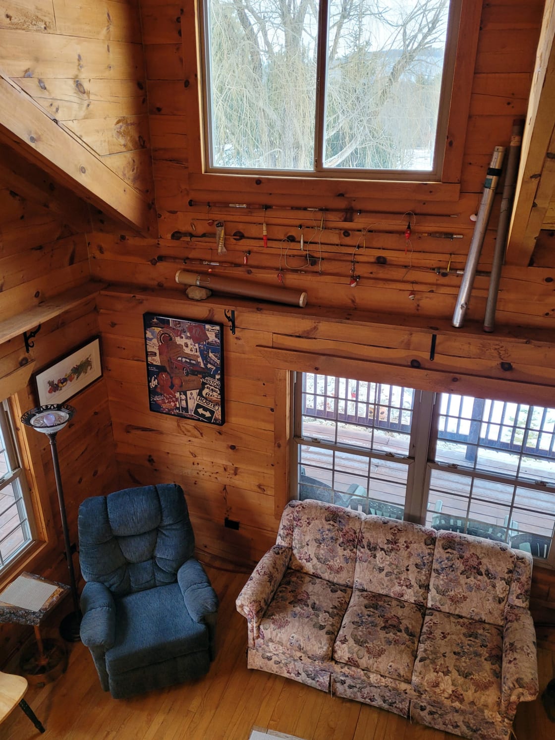 Looking down from 2nd floor sleeping loft to living room area. Antique fishing poles and original art grace the cabin. View out window is the Kickapoo Valley Reserve State Park.