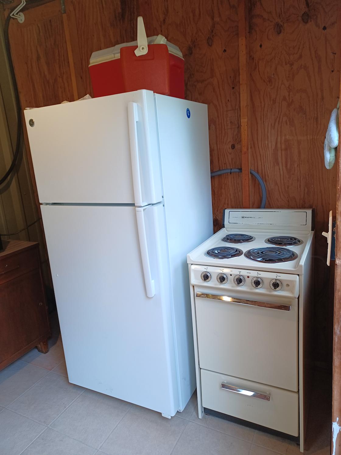 Full size fridge and freezer with apartment sized stove in shed with padlock (same key opens the padlock on the gate to drive into the property).  Stove can handle a 9x13 pan.  Metal pans in the drawer beneath it.
