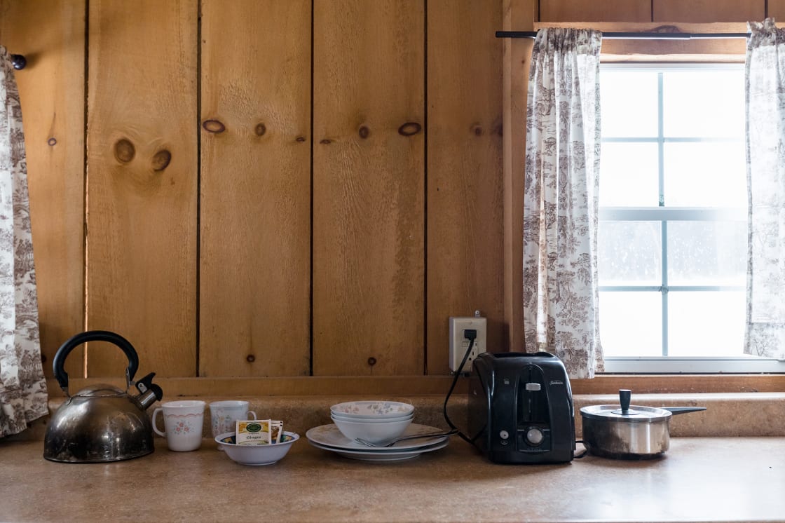 The cabin kitchen comes equipped with a toaster, kettle, pot, and various dishes for your stay. 