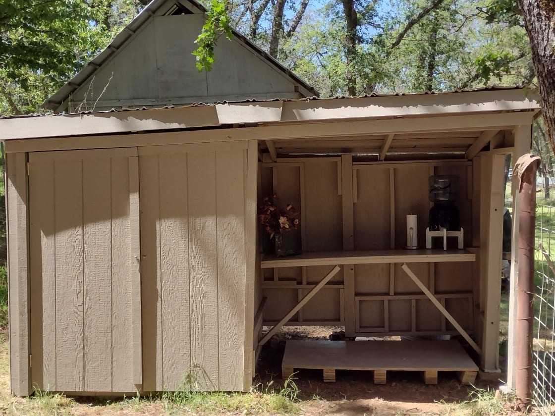 Shared outbuilding with toilet & tabletop with potable water.