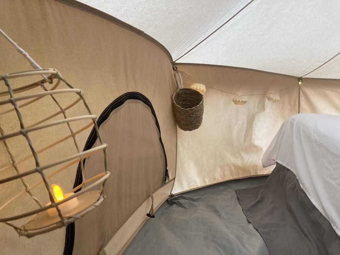 Soft lighting and a comfortable full-sized bed greet you inside La Belle Tent. We provide fresh sheets; please bring your own blankets & pillows. 