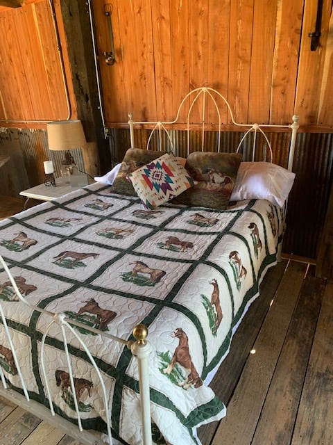 Cozy double bed made with crisp white linens on a vintage iron bed frame. 