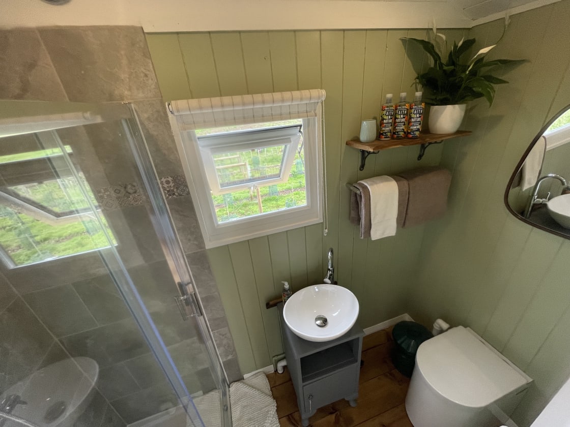 Bathroom with rain shower, sink, eco-loo. mirror and complimentary toiletries