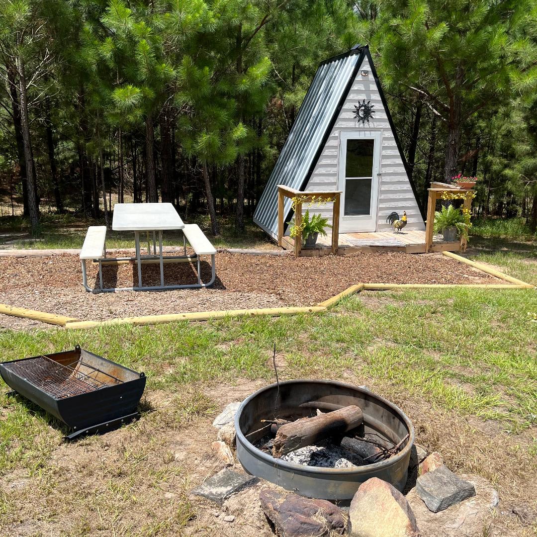 This is our small A-frame with a queen size bed and air conditioned. It also comes with a fire pit and camp grill. Perfectly cozy for 2 people. 