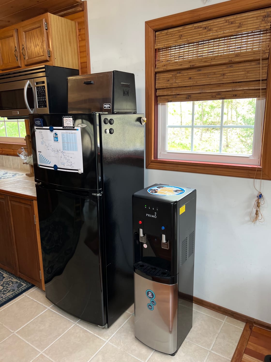 Far side of kitchen showing microwave, frig, and bottled water dispenser