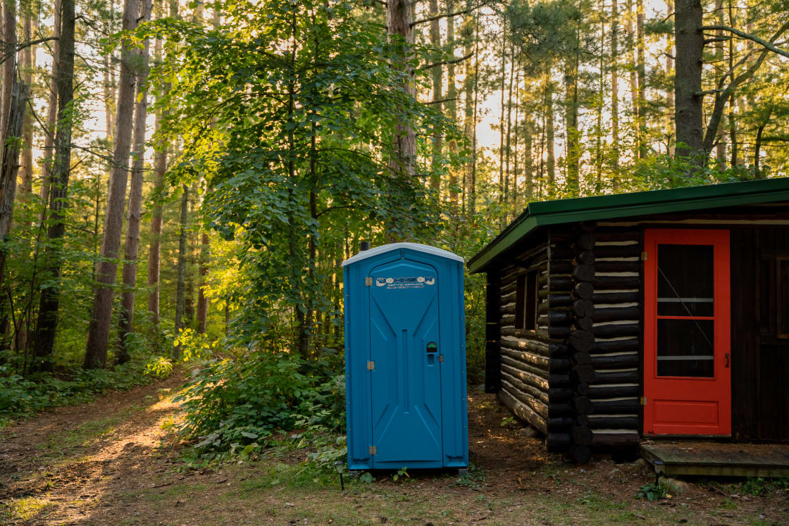 A clean outhouse is located at the back side of the cabin.