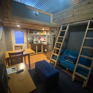 Main cabin area w/kitchenette, futon, table & retractable ladders to access sleeping area in the loft.