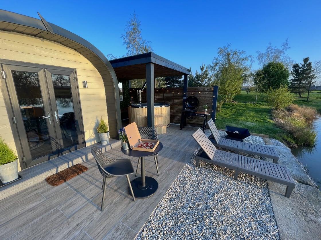 Your spectacular outdoor area consists of wood-fired hot tub, fire pit, BBQ, sun-loungers, table & chairs, fish from your your pod, lakeside & beautiful sunset views, pizzas can also be delivered to the site. 
