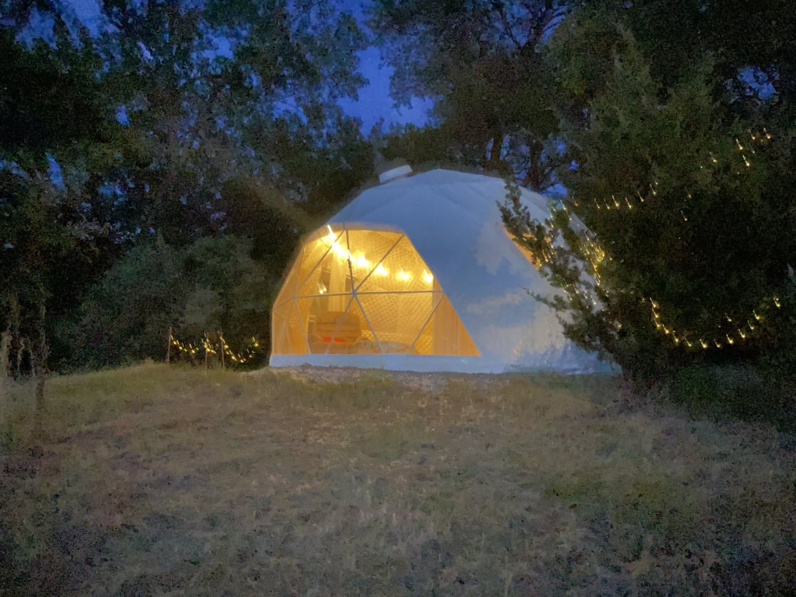 The Fantastic Geodesic tent during night with the lights on powered by a aolar battery.