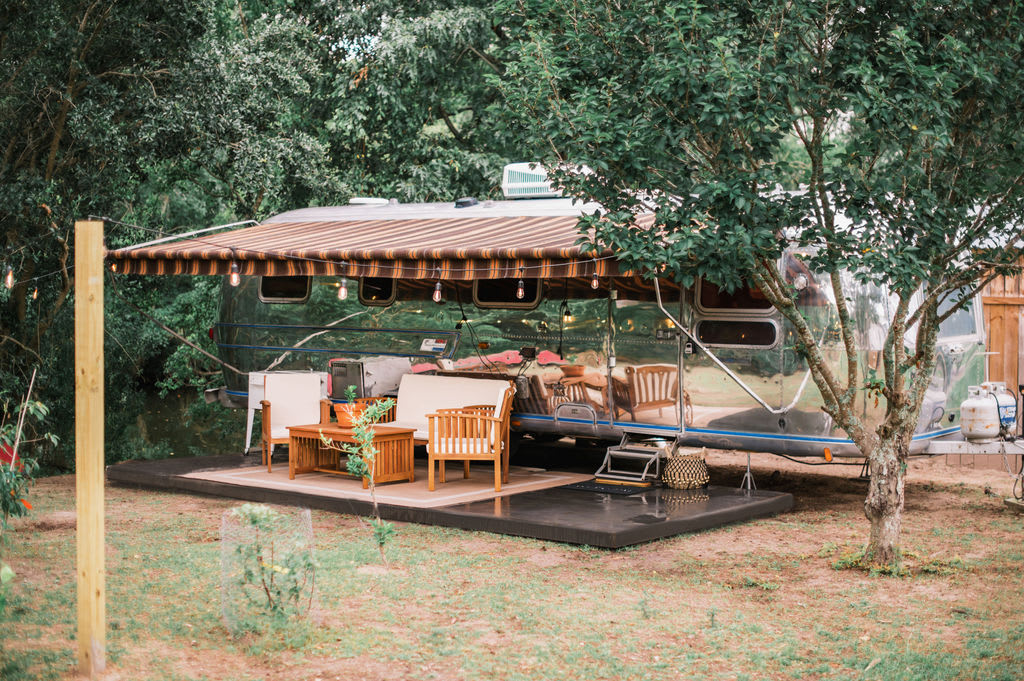 Our Airstream, nestled by our creek with a cozy outdoor sitting area. 