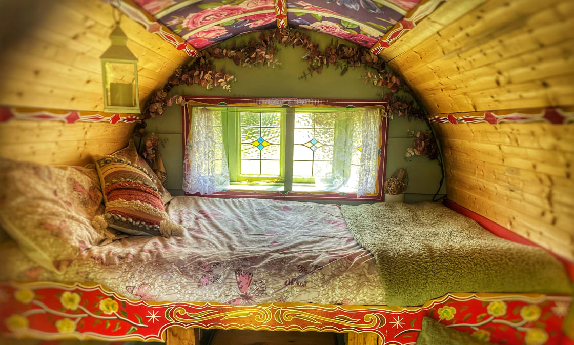 Cozy comfort of our bow top caravan's double bed, providing a dreamy sanctuary for a restful night's sleep amidst the beauty of nature.