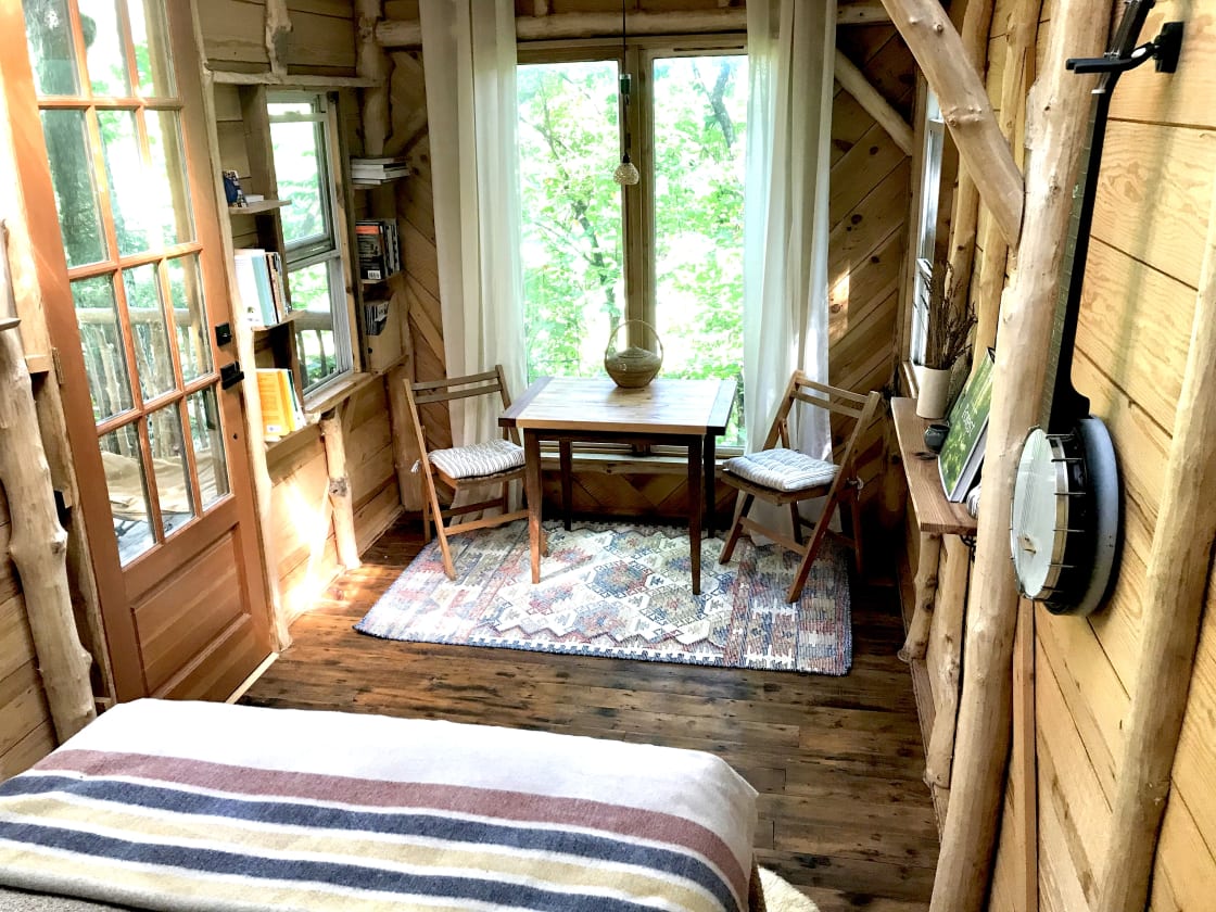 Inside treehouse with full-size mattress, table and chairs