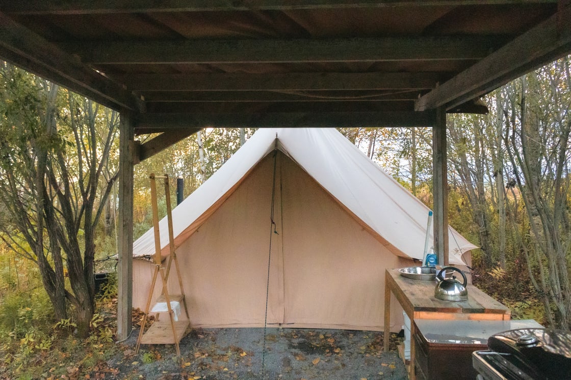 Canvas tent with protective awning and amenities.