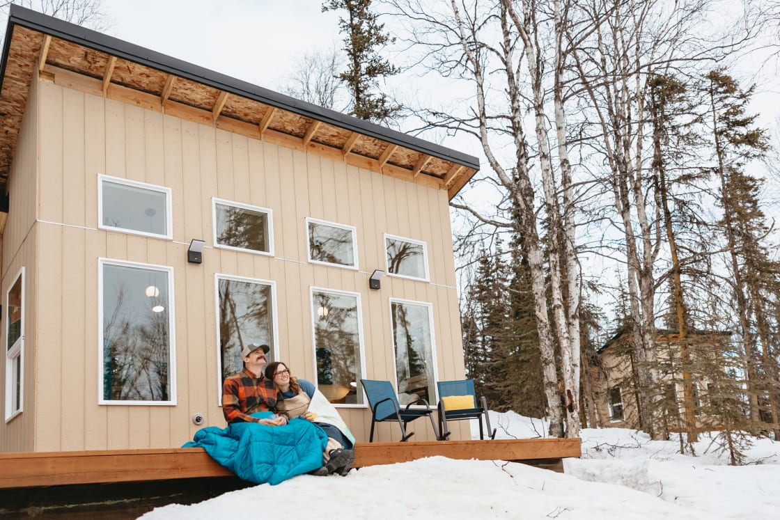 Our cozy wooden cabin nestled in a snowy wonderland, with large windows framing breathtaking views of nature's beauty. Envision yourself wrapped in warmth, sitting on the deck with blankets, and your loved one by your side. 
