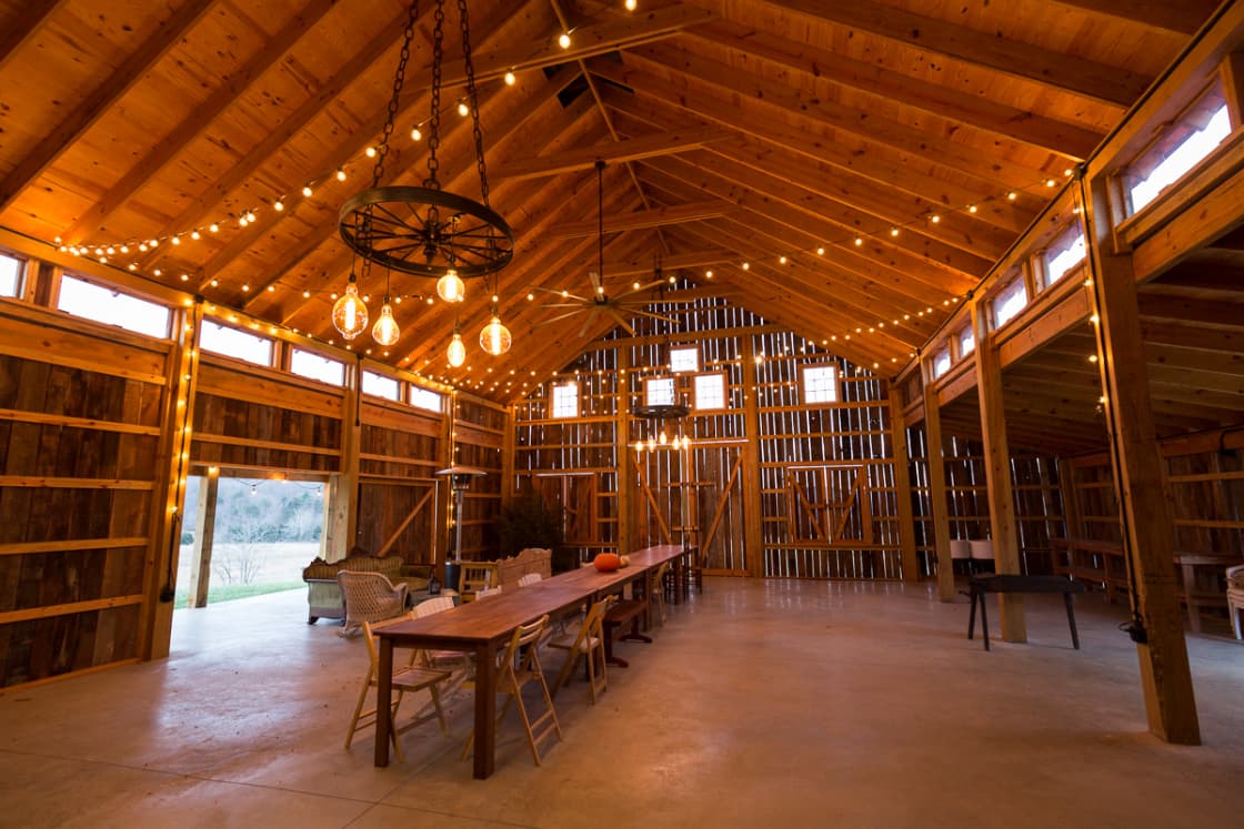 String lights and wagon-wheel chandeliers inside the barn. Very cool space!