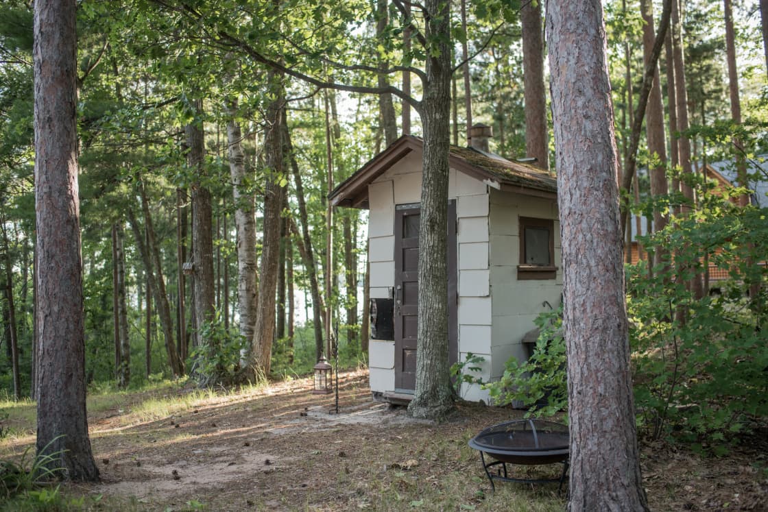 The outhouse is tucked in the trees and is clean and perfectly maintained