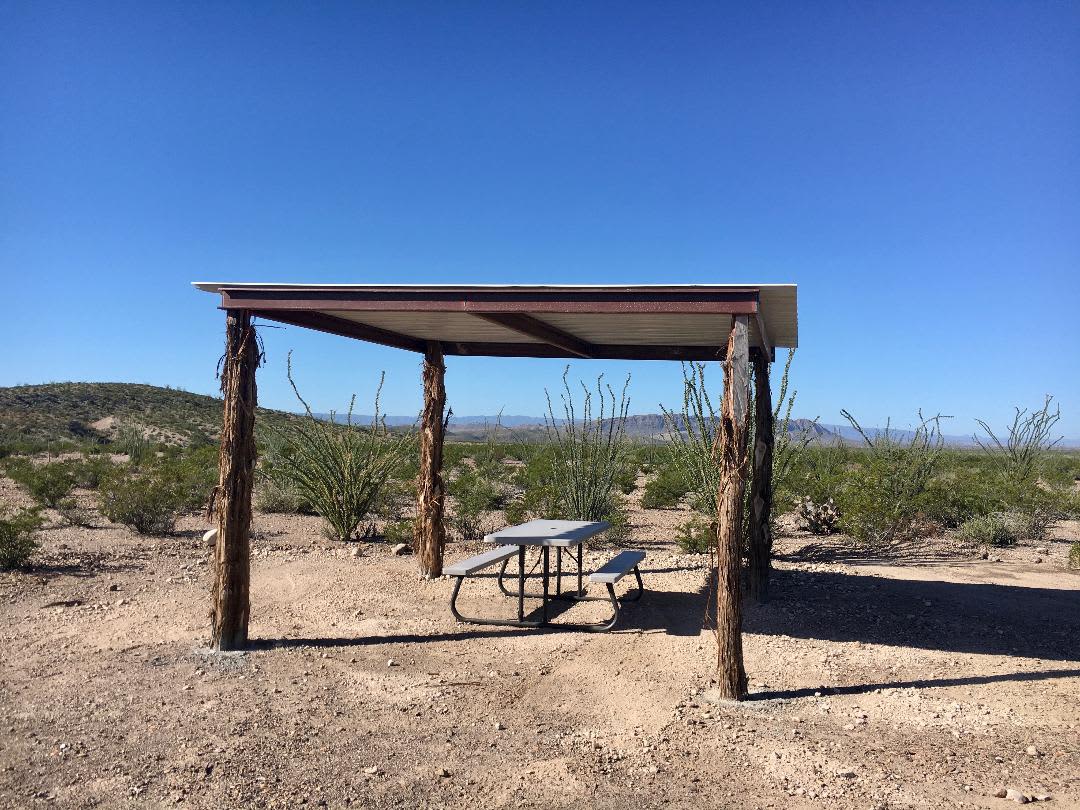 Shade Structure, picnic table (recently replaced with aluminum table), fire ring/grill, smoothed/leveled tent site, with a natural fence of ocotillo to frame your view of Chinati Peak and wide open views of Sierra Rica Mountain and Agua Adentro Mountain.
