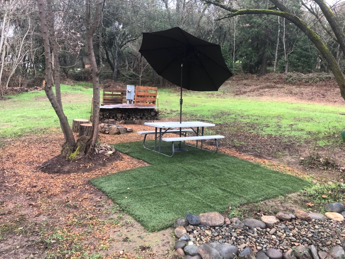 Campsite 2 with firepit, firewood, picnic table with umbrella and artificial grass. No power hookups available.