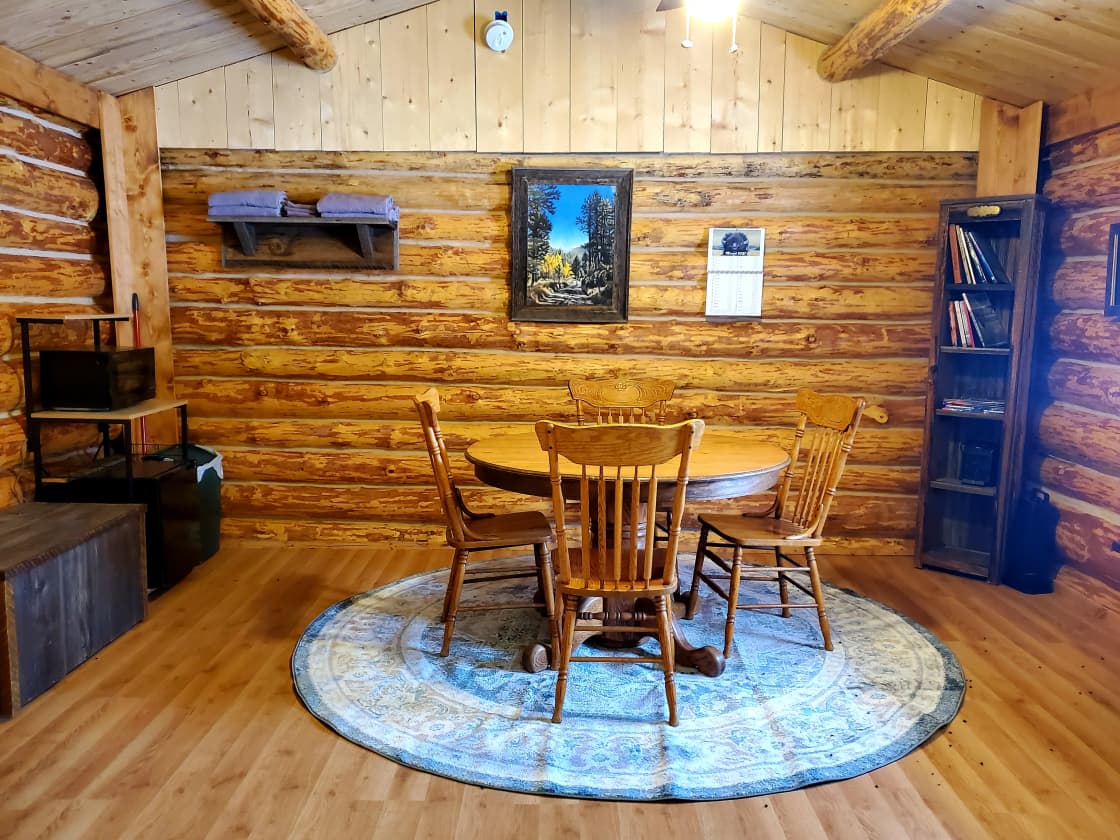 The inside of this camping log cabin with table, chairs, microwave and mini fridge