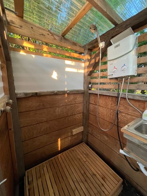 On-Demand Hot shower in Off-Grid custom bathroom with convenient wash basin. 