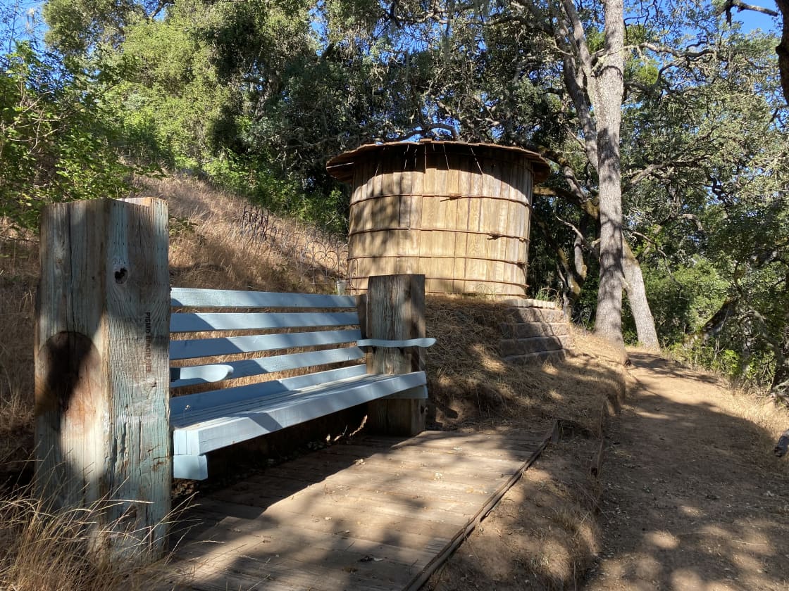 Old fashioned water tank and a bench to rest on.
