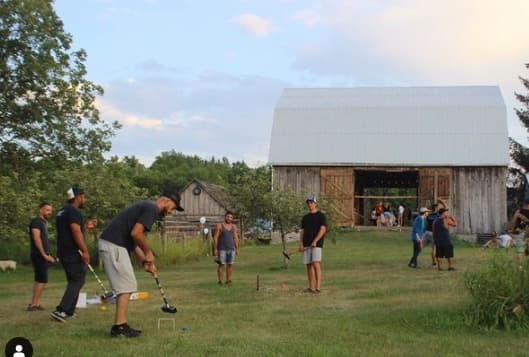 Friends enjoying a game of croquet by the barn.