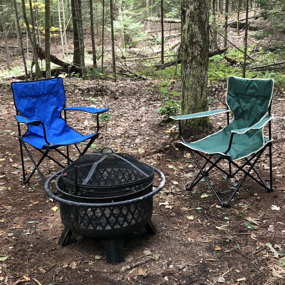 Each campsite has two chairs and a firepit with a grill.