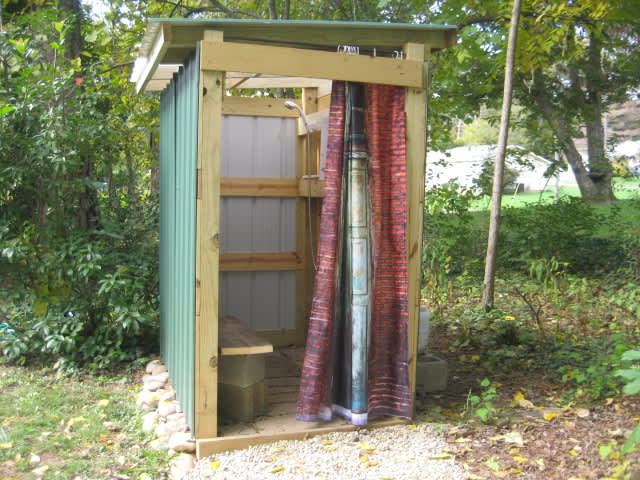 Outdoor shower with changing half, bench and clothes hooks. Propane in-line water heater.