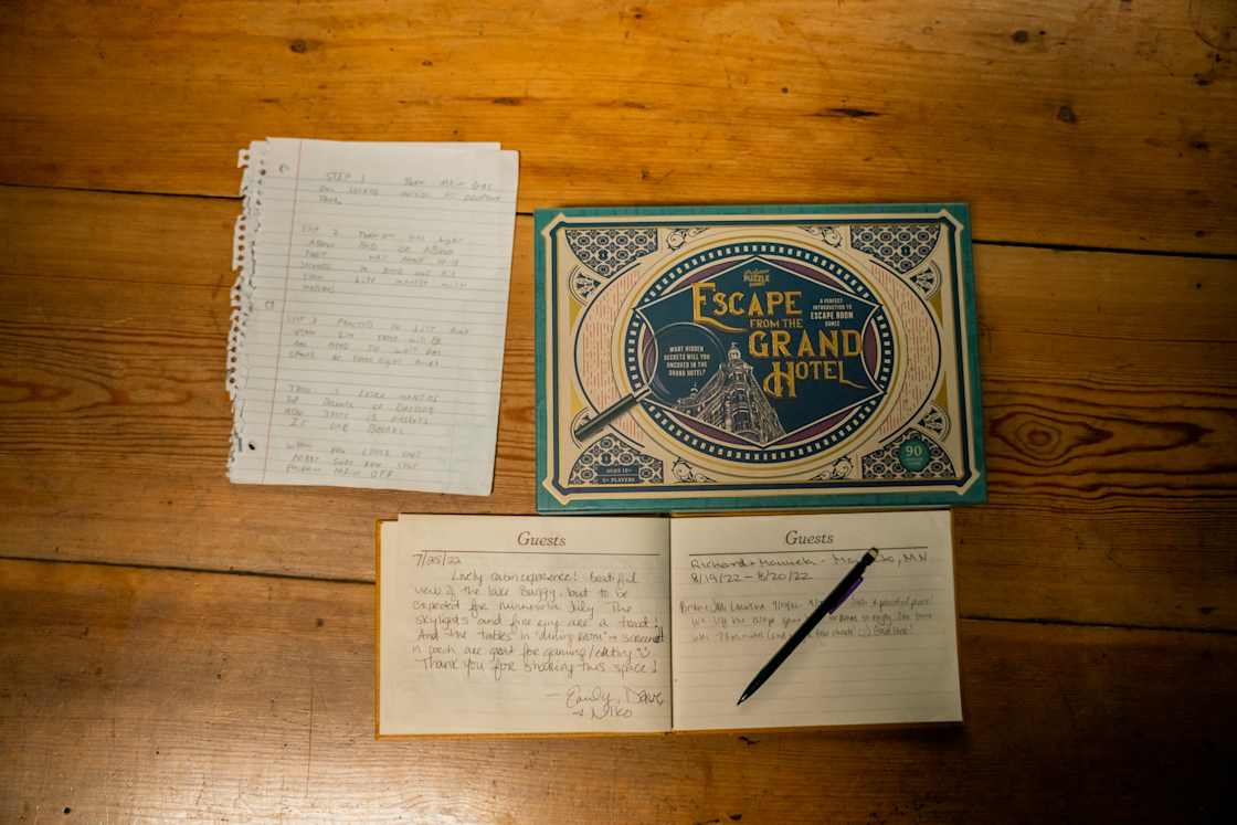 Instructions, a game generously gifted from a previous guest, and the guestbook are on the dining table in the cabin.
