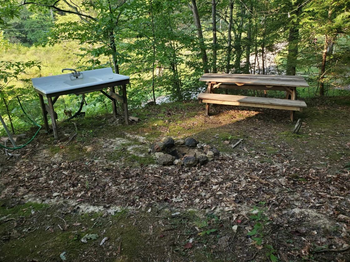 Farmhouse sink, fire pit, and seven-foot picnic table overlooking the meadow
