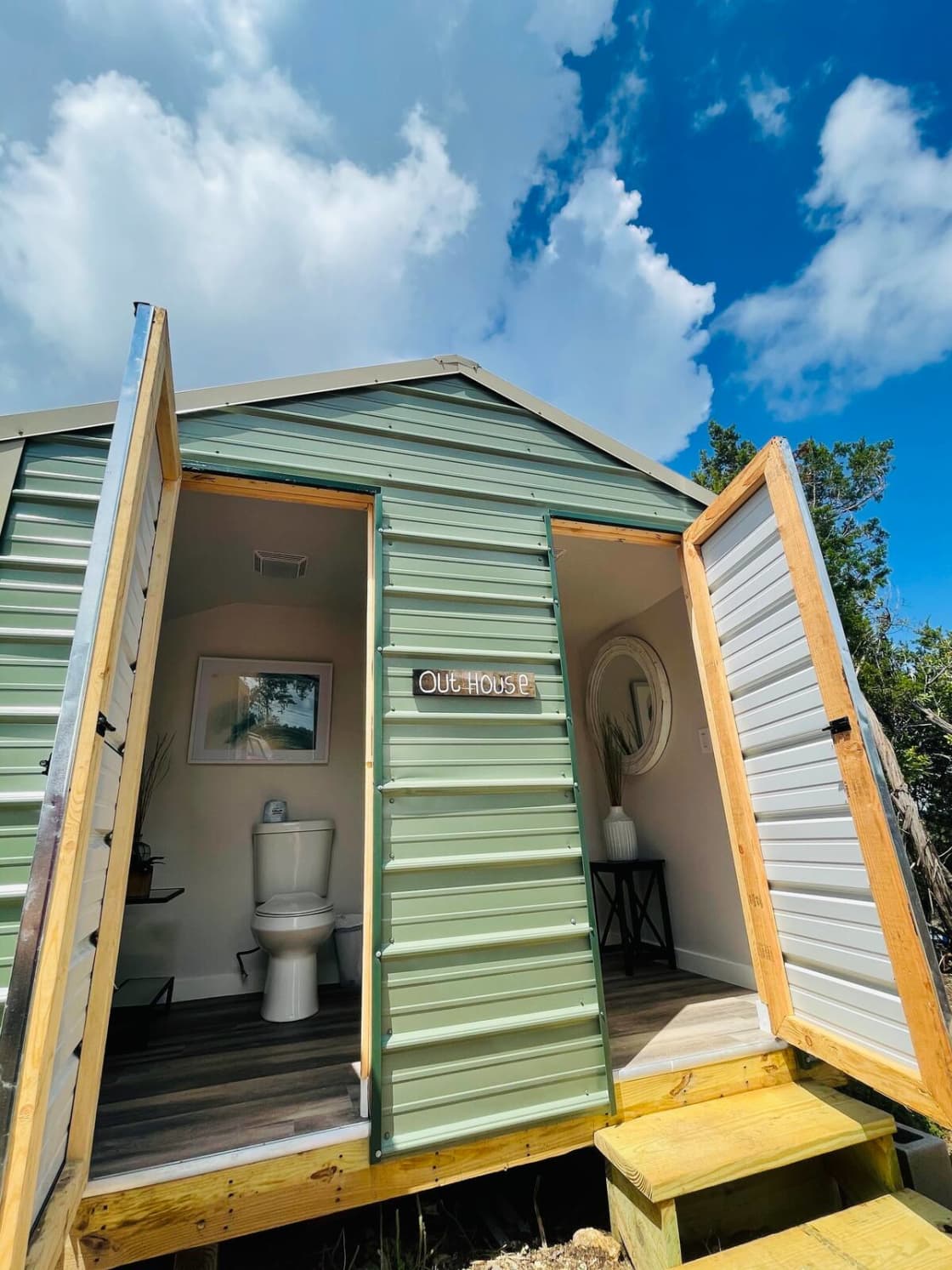 Outhouse with 2-separate stalls with porcelain flushing toilets and hand-sanitizer. Outside is a hand-washing sink!