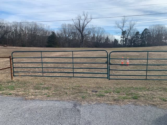 The entrance from Hwy 5 is a wide driveway with double green gates.