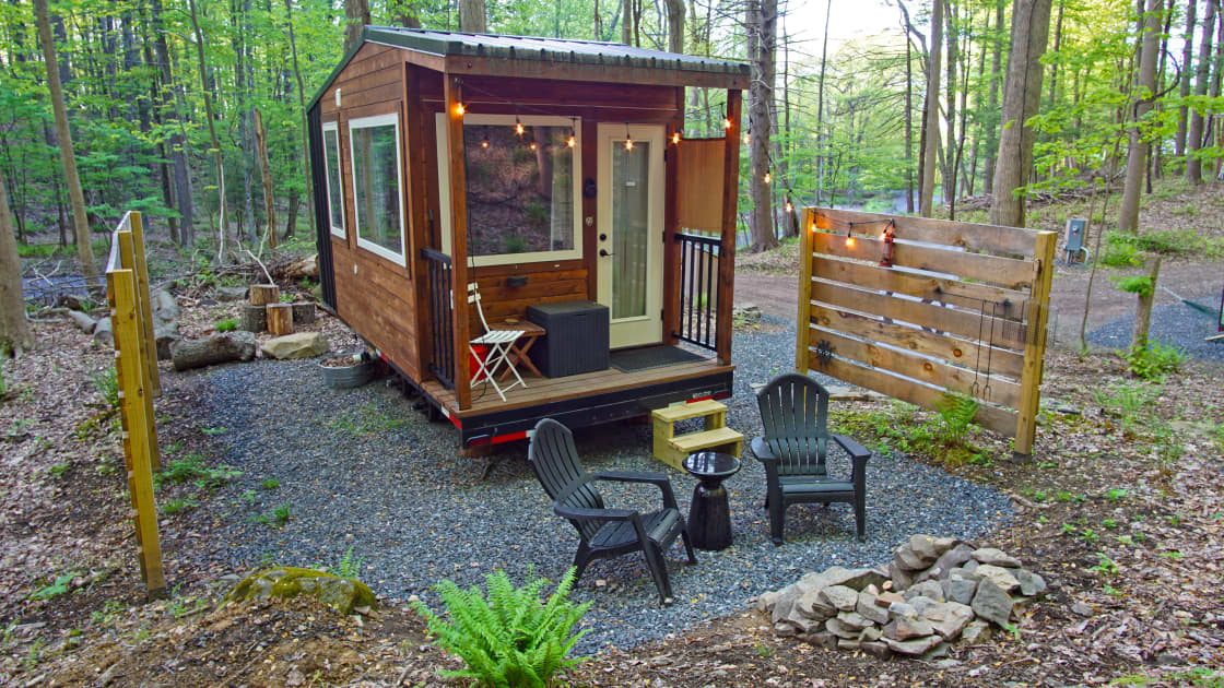 Front view of the tiny home with a small porch and private seating and fire pit area