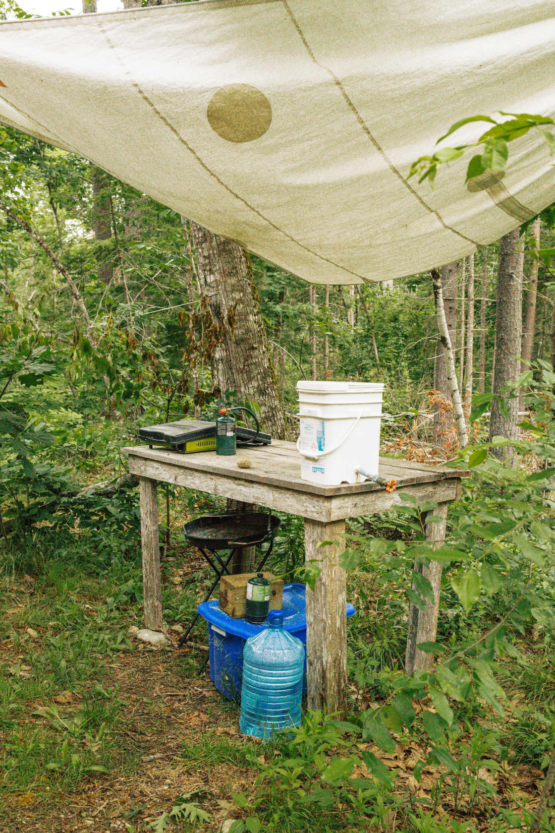 There is a covered cooking area with a charcoal grill and camping stove. 