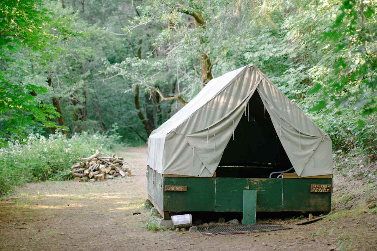 A canvas tent on a platform that is located just along the creek