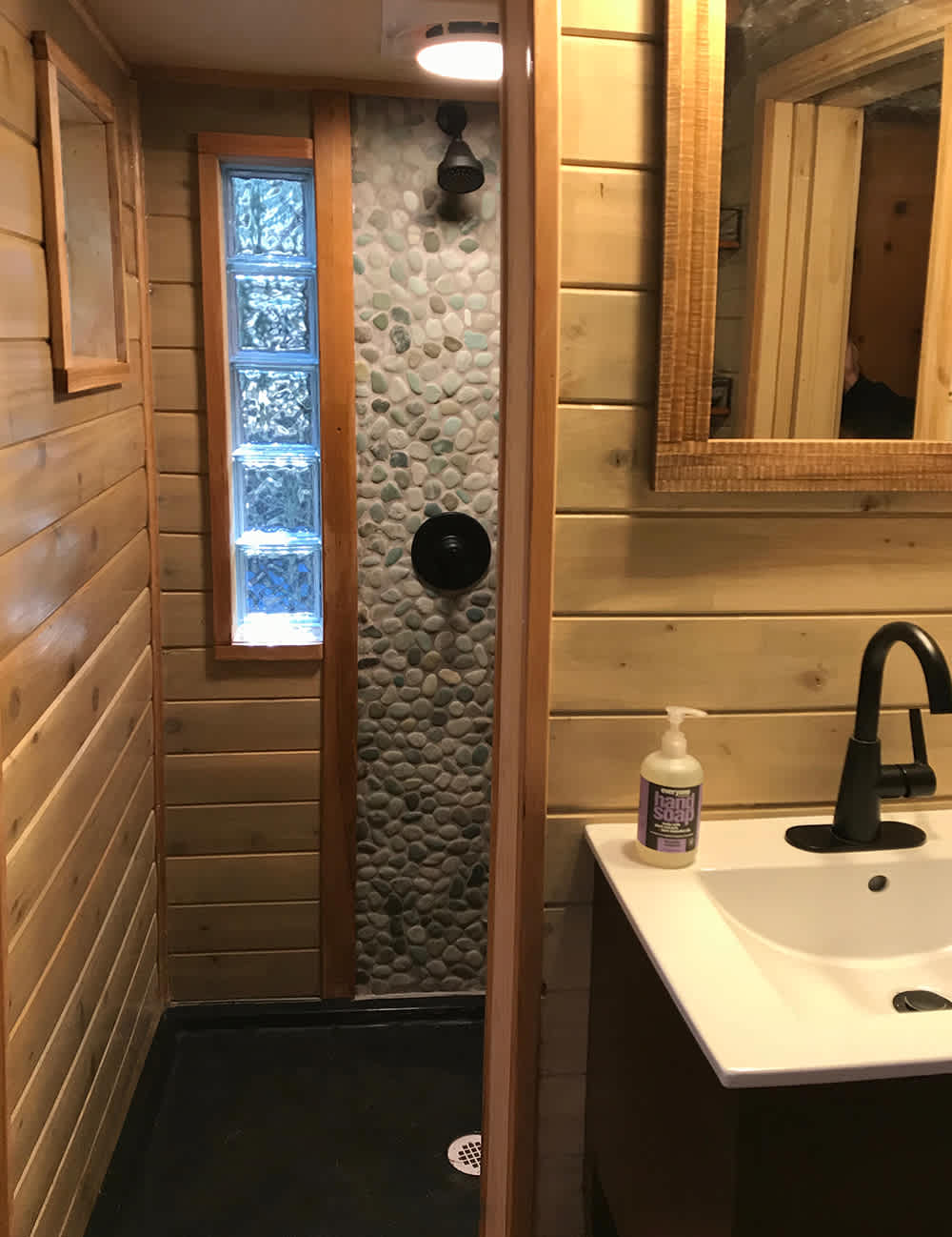 Step down into a shower that features a river stone wall with glass block windows