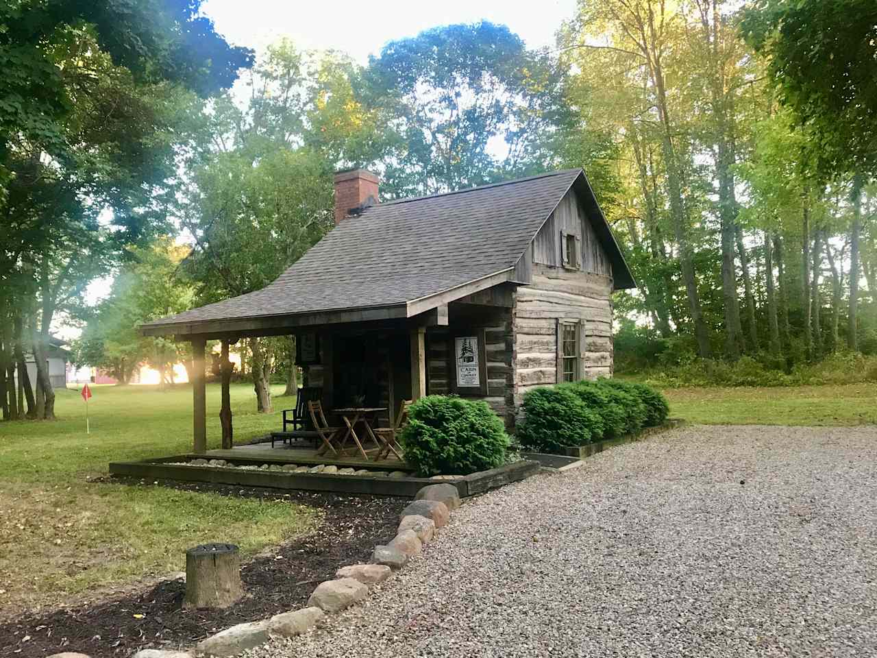 View of cabin and gravel area where camping unit will be parked.